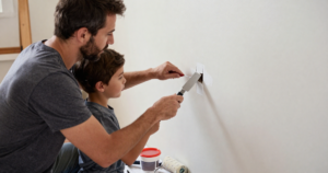father and son patching hole in wall